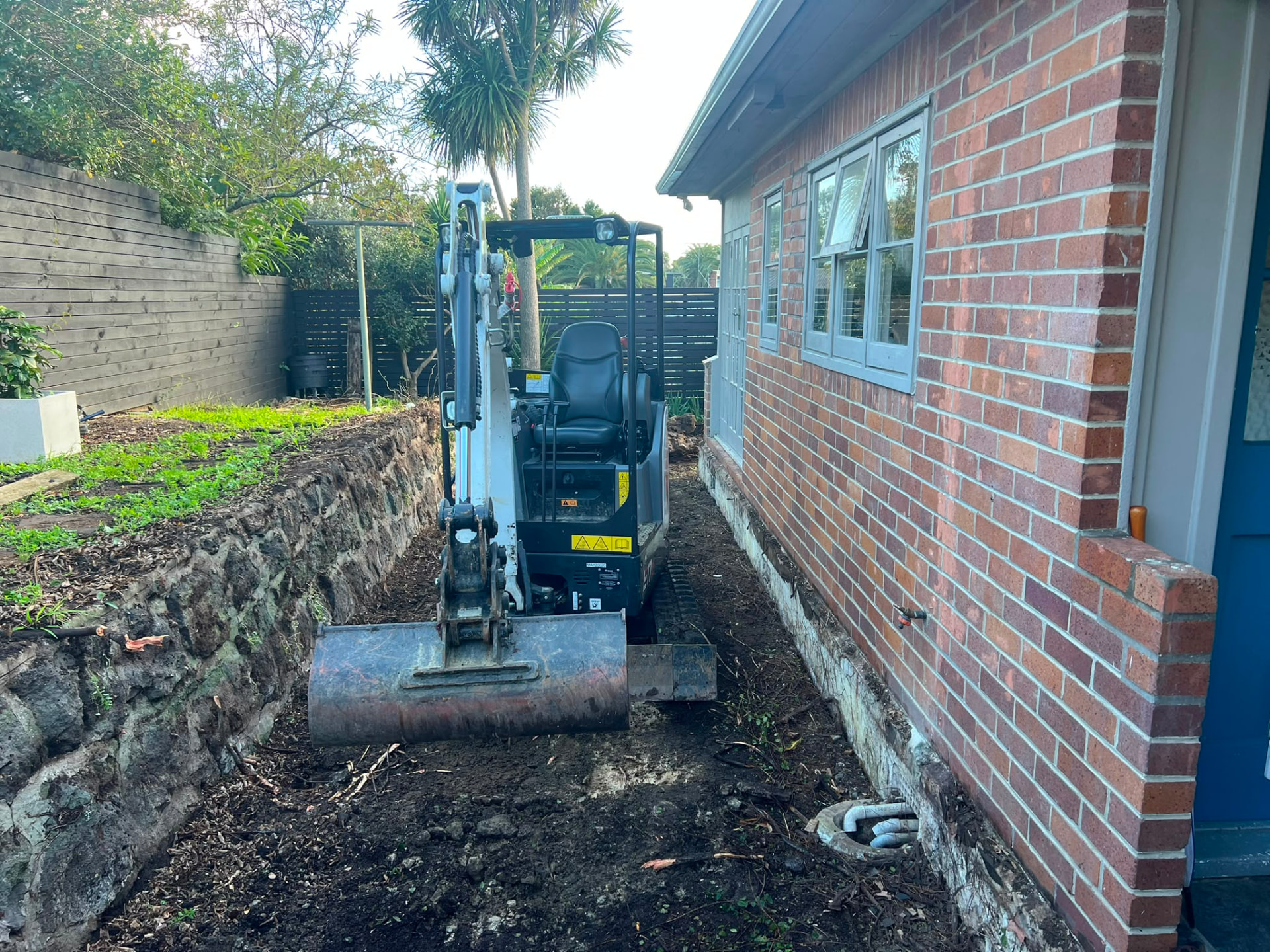 Mini excavator trenching in a tight access side yard